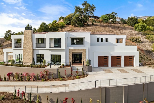 view of front facade featuring driveway, a chimney, and stucco siding