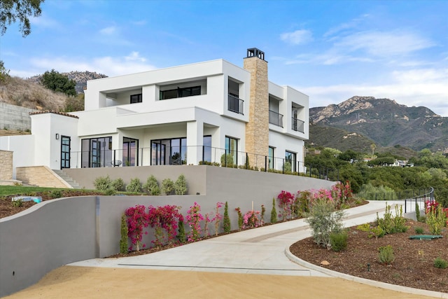 exterior space with a chimney, fence, a mountain view, and stucco siding