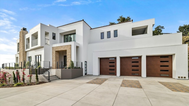 contemporary home with driveway, stone siding, a garage, and stucco siding