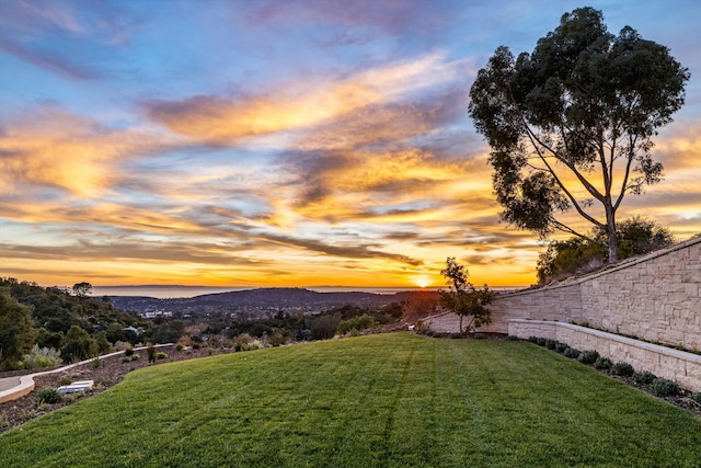 yard at dusk featuring fence and a mountain view