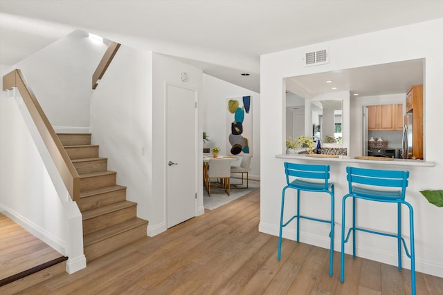 kitchen with light hardwood / wood-style floors, light brown cabinetry, and stainless steel refrigerator