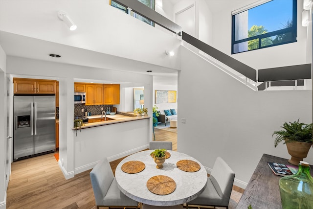 dining area with light hardwood / wood-style floors and a high ceiling