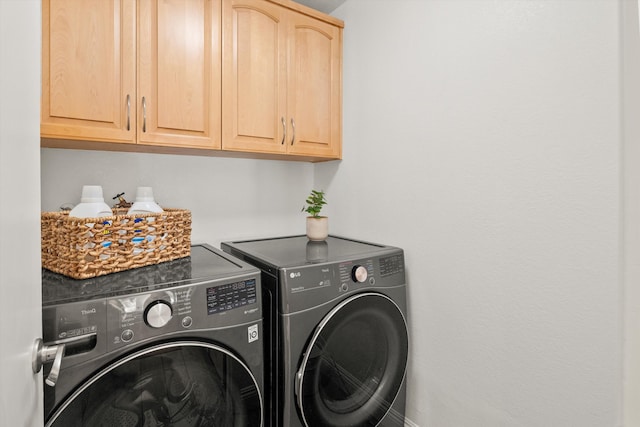 clothes washing area featuring washer and dryer and cabinets