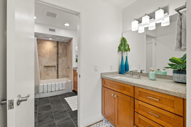 bathroom featuring tile patterned flooring, vanity, and tiled shower / bath