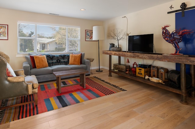 living room with a barn door and hardwood / wood-style flooring