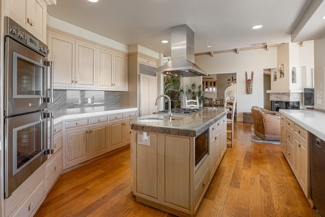 2408 Latigo Dr, Solvang, CA 93463 - kitchen featuring a center island with sink, multiple ovens, light hardwood / wood-style flooring, decorative backsplash, and island exhaust hood