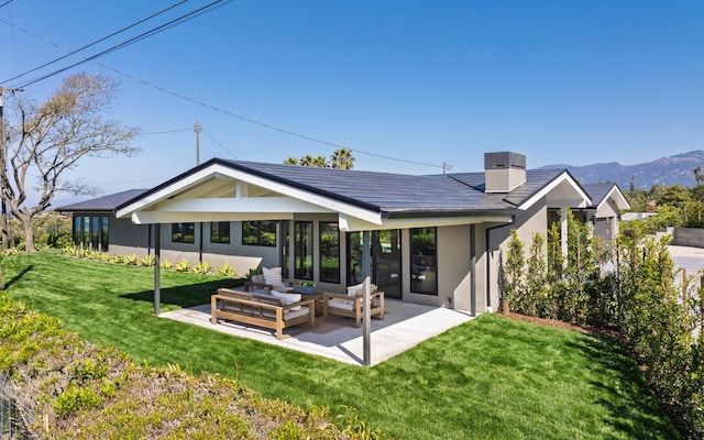 rear view of property with outdoor lounge area, stucco siding, a patio, a lawn, and a mountain view