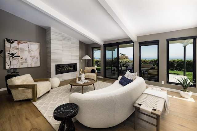 living room with wood finished floors, vaulted ceiling with beams, baseboards, and a tile fireplace