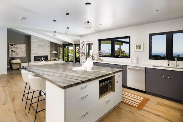 kitchen featuring lofted ceiling, light wood finished floors, a kitchen breakfast bar, stainless steel appliances, and a sink