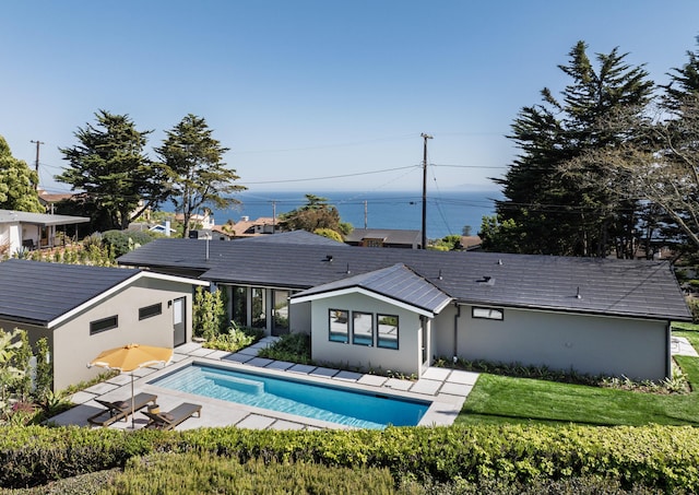 back of property with stucco siding, an outdoor pool, a patio, and a lawn