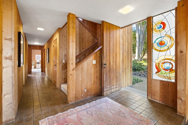 entrance foyer featuring dark tile patterned flooring and wood walls