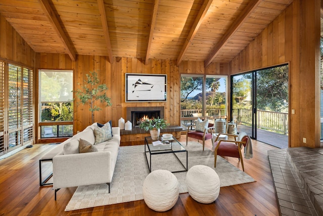 living room with vaulted ceiling with beams, wood ceiling, and a tiled fireplace