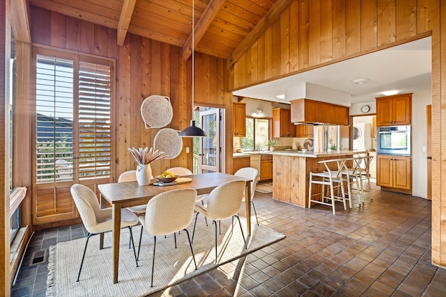 tiled dining space with vaulted ceiling with beams, wood walls, and wood ceiling