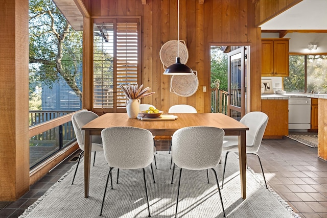 dining area with dark tile patterned flooring and wood walls