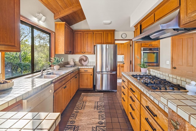 kitchen with tile countertops, stainless steel appliances, wood ceiling, and range hood