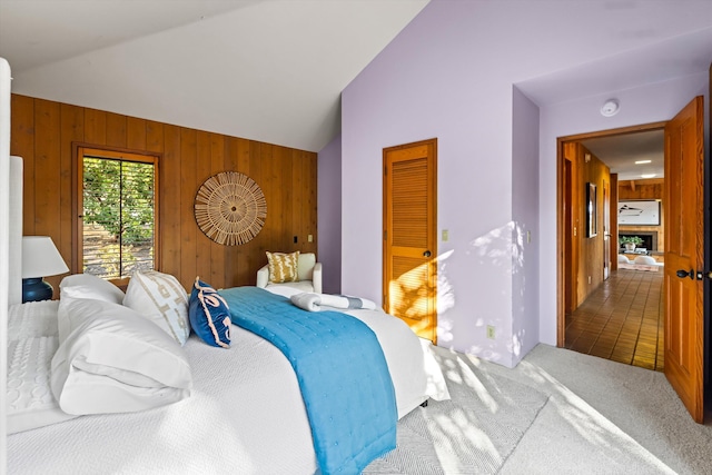 carpeted bedroom with vaulted ceiling and wooden walls