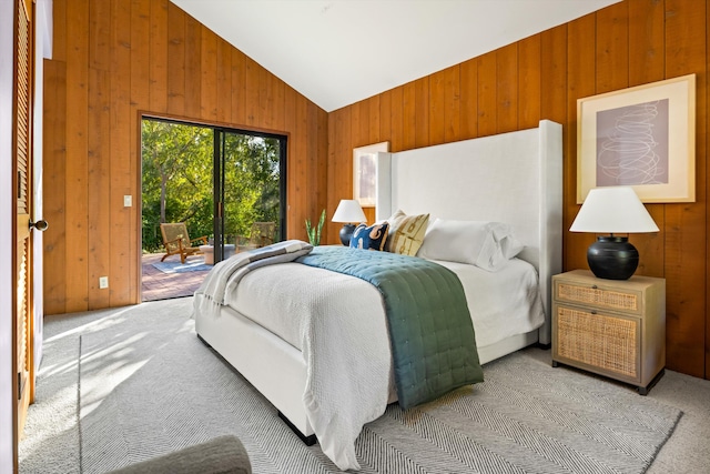 carpeted bedroom featuring access to exterior, vaulted ceiling, and wood walls