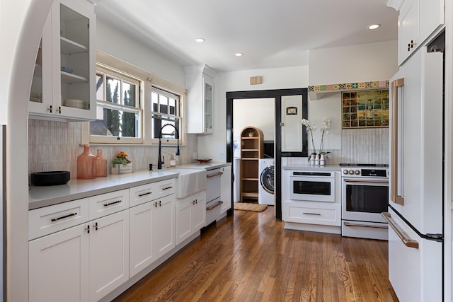 kitchen with white cabinetry, backsplash, white appliances, and washer / dryer