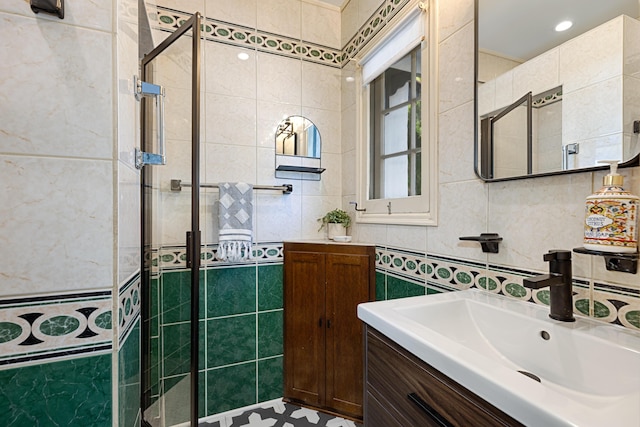 bathroom featuring vanity, a shower with door, and tile walls