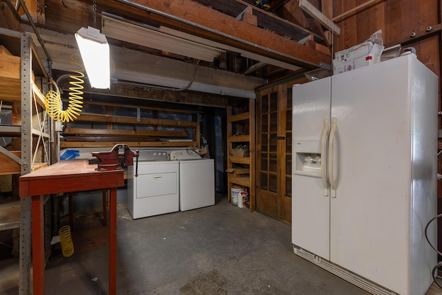 basement with separate washer and dryer, white fridge with ice dispenser, and a workshop area