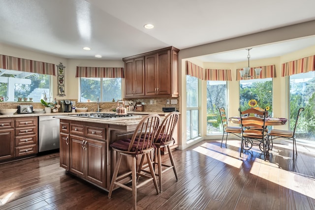 kitchen featuring decorative backsplash, appliances with stainless steel finishes, dark wood-type flooring, decorative light fixtures, and a center island