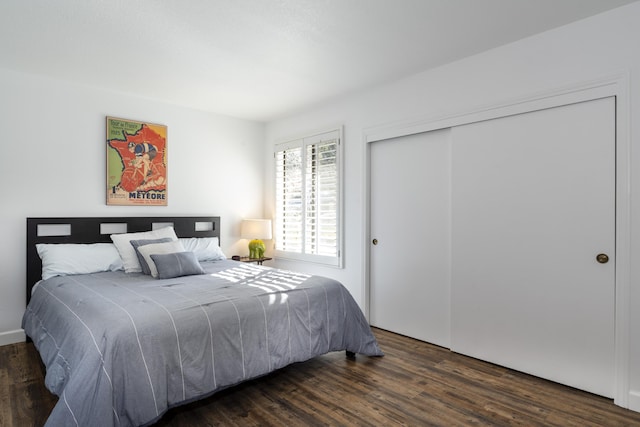 bedroom with dark wood-type flooring and a closet