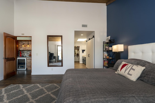 bedroom with bar area, a towering ceiling, wine cooler, and dark wood-type flooring