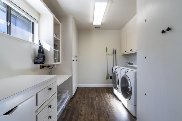 laundry area featuring washing machine and clothes dryer, cabinets, and dark hardwood / wood-style floors