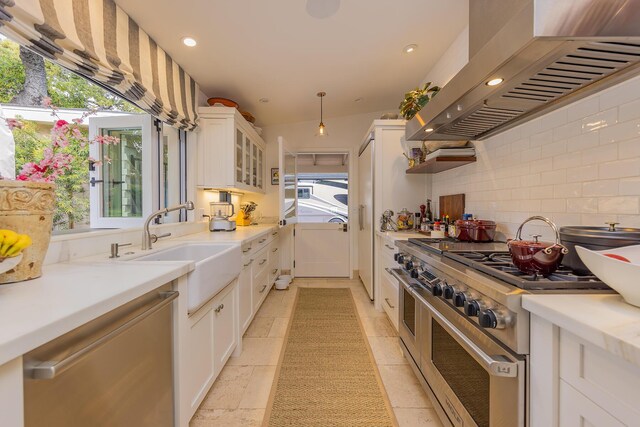 708 Cuyama Rd, Ojai, CA 93023 - kitchen with white cabinetry, range with two ovens, wall chimney range hood, and a healthy amount of sunlight