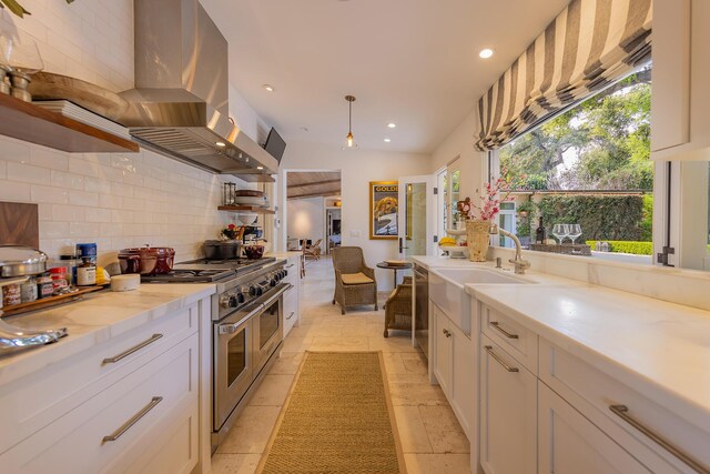 708 Cuyama Rd, Ojai, CA 93023 - kitchen featuring tasteful backsplash, wall chimney exhaust hood, stainless steel appliances, decorative light fixtures, and white cabinetry