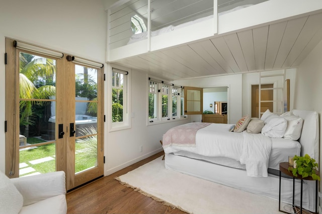 bedroom with hardwood / wood-style floors, access to exterior, multiple windows, and french doors