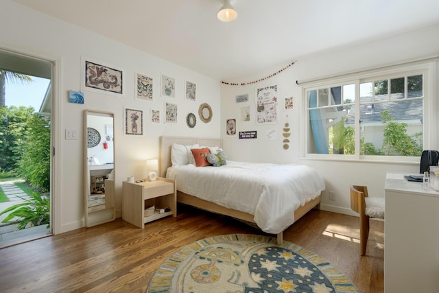 bedroom with access to exterior, dark hardwood / wood-style flooring, and multiple windows