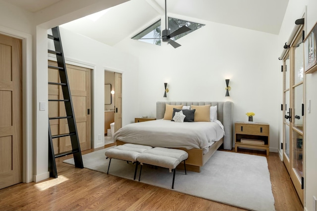 bedroom with ensuite bath, ceiling fan, light hardwood / wood-style floors, and vaulted ceiling