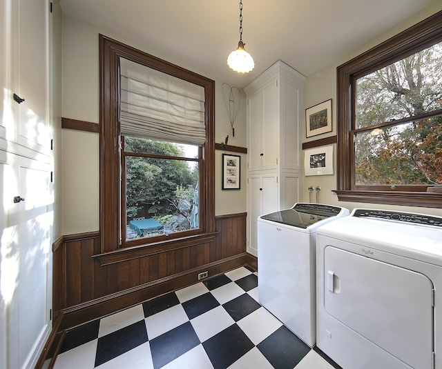 laundry room featuring wood walls, washing machine and clothes dryer, and cabinets