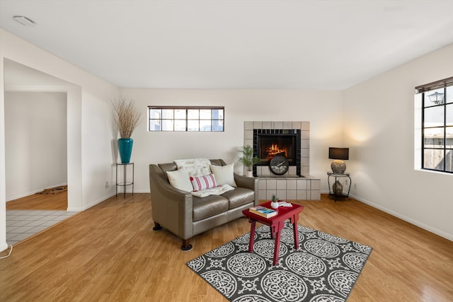 living room featuring light wood-type flooring and a tiled fireplace