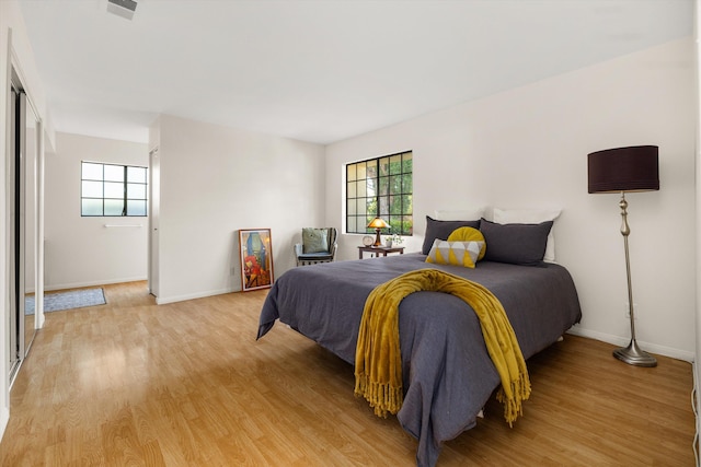 bedroom with light wood-type flooring and multiple windows