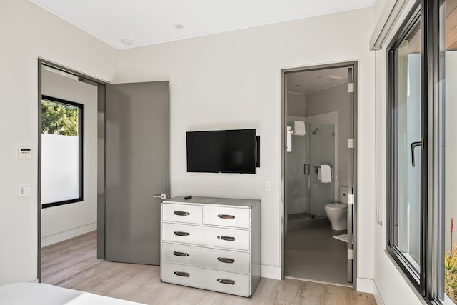 bedroom featuring light wood-type flooring and ensuite bath