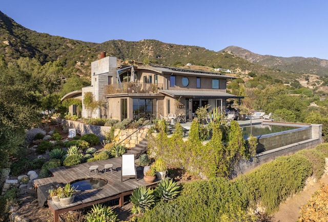 rear view of house with a mountain view, a balcony, and a patio area