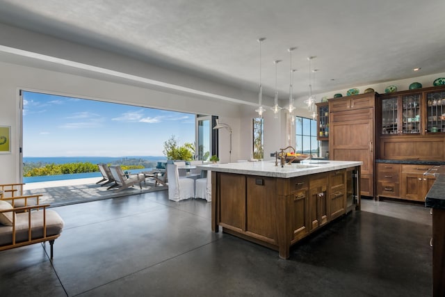 kitchen with a kitchen island with sink, sink, and decorative light fixtures