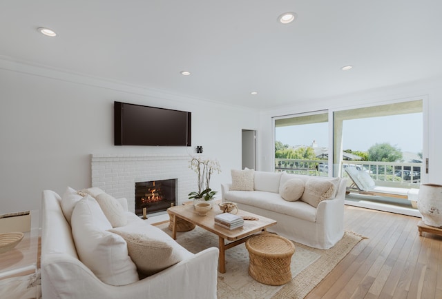 living room featuring crown molding, a fireplace, and light hardwood / wood-style flooring