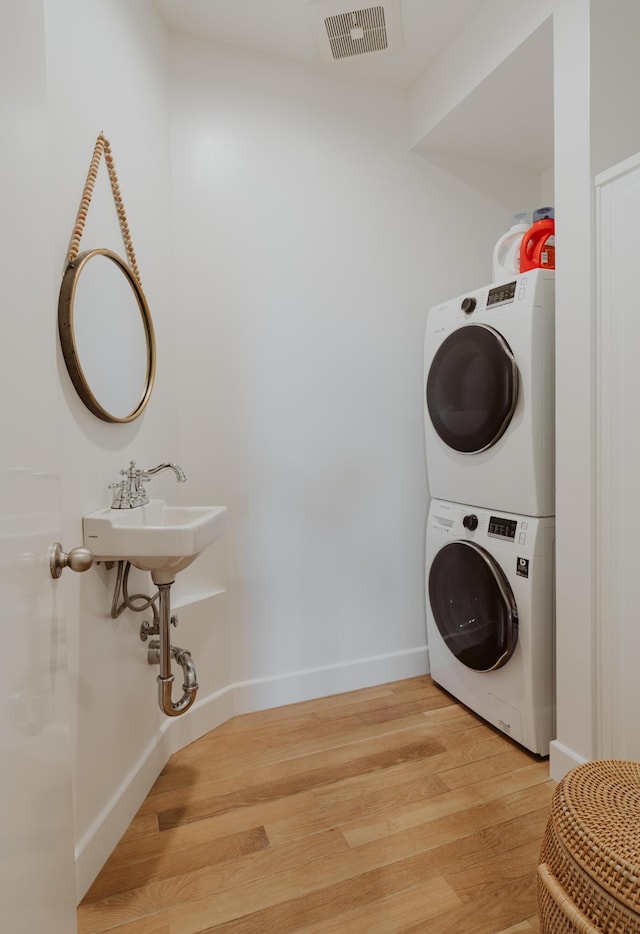 laundry area with stacked washer and clothes dryer and hardwood / wood-style floors