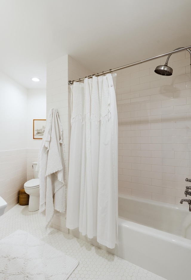 bathroom featuring tile patterned flooring, shower / bath combo, tile walls, and toilet