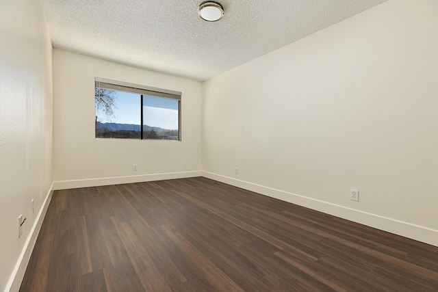 spare room with dark wood-type flooring and a textured ceiling