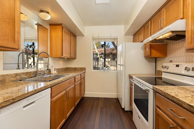 kitchen with white appliances, dark hardwood / wood-style floors, light stone counters, and sink