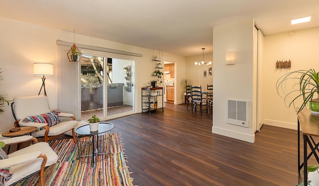 living room with an inviting chandelier, a textured ceiling, and dark hardwood / wood-style flooring