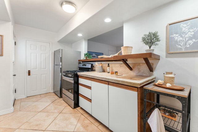 kitchen featuring stainless steel gas stove, white cabinets, and light tile patterned floors