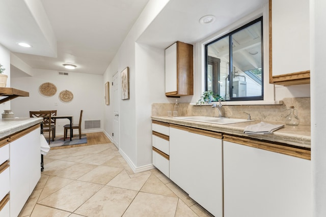 kitchen with sink, white cabinetry, and light tile patterned flooring