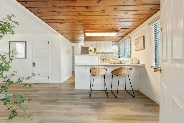 kitchen with white cabinets, a kitchen bar, wood ceiling, and kitchen peninsula