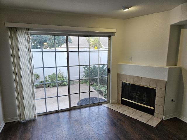 unfurnished living room with wood-type flooring and a tiled fireplace