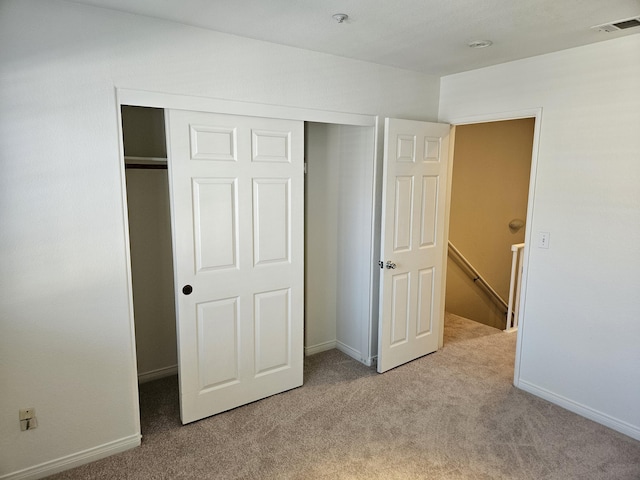 unfurnished bedroom featuring light colored carpet and a closet